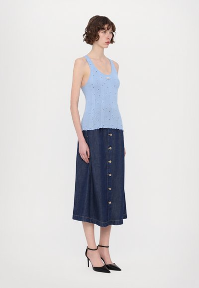 Lyseblå ribbet strikket tanktop med bølget hem, parret med et langt denimskjørt med frontknapper og svarte spisse hæler.