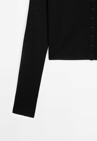 Cardigan en maille noire à manches longues avec de petits boutons noirs sur le devant, présenté sur fond blanc.