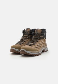 Bruine wandelschoenen met een nylon bovenkant, rubberen zolen en grijze accenten. Beschikt over stevige veters en een hoge enkelontwerp voor extra ondersteuning.