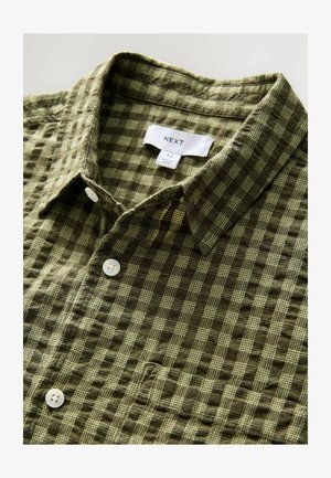 Grün kariertes Kurzarmhemd aus weichem Stoff, mit einem Button-Down-Kragen und weißen Knöpfen, versehen mit einem Etikett und Größenschild.