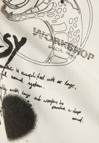 Vit tyg med svarta tryckta grafiker och text. Inkluderar abstrakta former och handskrivna anteckningar, vilket skapar ett strukturerat, lager-på-lager utseende.