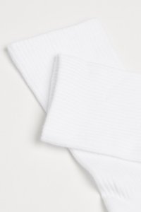 Hvide bomuldsokker med en ribbet overflade og en blød finish, der overlapper for at fremhæve deres ensartede farve og design detaljer.