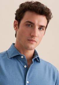 Blauwe denim overhemdbloes met een gespreide kraag, voorzien van witte knopen en een soepele, middelgewicht textuur.