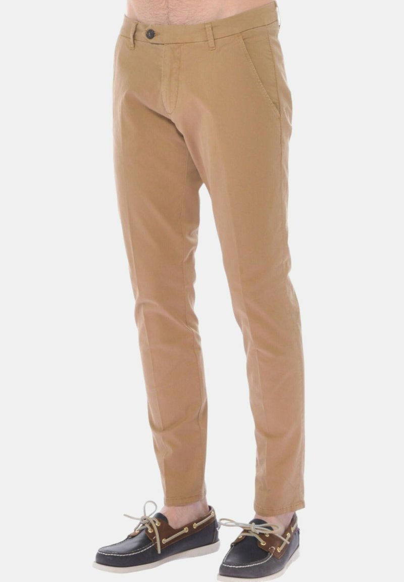 Pantaloni di cotone marrone chiaro con vestibilità dritta, dotati di zip e chiusura a bottone, tasche laterali e una texture liscia.