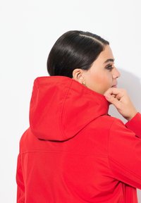 Rode hoodie-jack met een gladde textuur, voorzien van een eenvoudig ontwerp en stiksel-details. Iets gedraaid gedragen, waardoor de achterkant zichtbaar is.