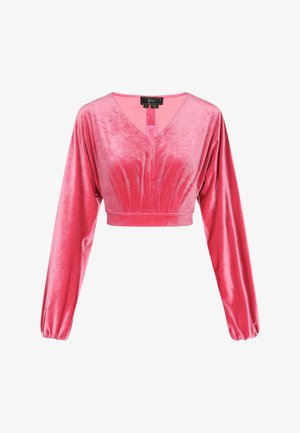 Lyserød fløjl cropped top med lange, puffede ærmer og en V-halsudskæring. Har folder foran og en nøglehulsdetail bagpå med en frynse.