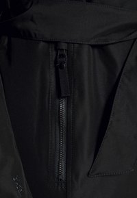 Czarna kurtka z tkaniny z zamkiem błyskawicznym z przodu, gładką fakturą oraz kieszenią z klapką z subtelnymi detalami przeszycia.