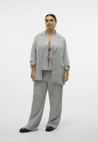 Lichtgrijze driekleurige outfit bestaande uit een op maat gemaakt blazer, een cropped top met striksluiting en een broek met wijde pijpen. Zachte textuur, minimale patronen.