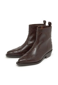 Botines de cuero marrón con punta afilada, que presentan diseños decorativos recortados, tiradores y un tacón bajo y cuadrado.