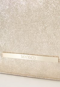 Metallic gold handbag featuring a textured surface, a gold hardware nameplate, and a sleek rectangular shape with minimal accents.