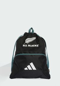 Mochila negra con cordón y acentos en azul verdoso, con el logo de "ALL BLACKS" y el trébol blanco de Adidas en la parte frontal. Tejido texturizado.