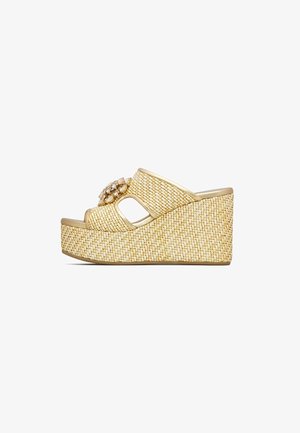 Sandalo con zeppa beige intrecciata con punta aperta, ritaglio laterale e decorazione gioiello sulla fascia superiore.