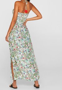 Blomstermønstret maxi-kjole i let stof, med en smocked bodice, halterneck med rød frynse og slid i siden for bevægelse.