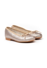 Bailarinas doradas brillantes con punta redondeada, suave ribete beige y un lazo en la parte delantera. Suela plana con un tacón mínimo.