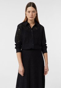 Black lace dress with intricate floral patterns, featuring a button-up collar, long sleeves, and a cinched waist design. Smooth texture.