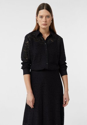 Black lace dress with intricate floral patterns, featuring a button-up collar, long sleeves, and a cinched waist design. Smooth texture.
