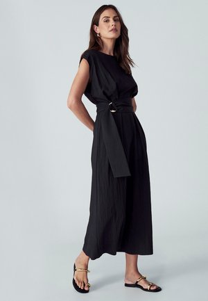 Juoda, iki kelių ilgio suknele, laisvo kirpimo, trumpomis rankovėmis ir surišamu juosmens diržu. Ypatumai: lygus, tekstūruotas audinys ir apvalus iškirpimas.