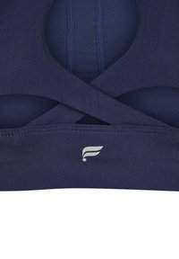 Navyblauer Sport-BH aus strukturiertem Material, mit einem Kreuzträgerdesign und einem silbernen Logo in der Mitte unten. Flache Nähte erhöhen den Komfort.