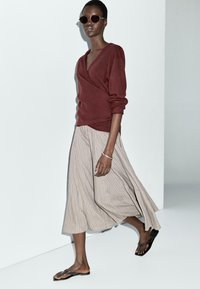 Burgundy wrap sweater, light brown pinstriped skirt, flat black sandals, paired with round sunglasses. Smooth fabric, loose fit.