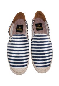 Zapatos de lona de rayas azules y blancas sin cordones, con una suela de yute trenzado y detalles en cuero marrón en el talón. El interior presenta un patrón de puntos.