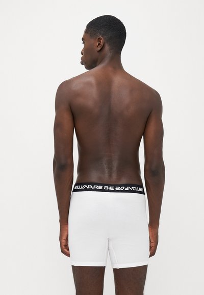 Boxer briefs brancos com um cós elástico preto apresentando o logótipo "Billionaire Boys Club", textura suave e design ajustado.