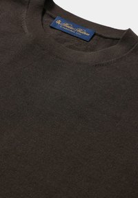 Maglione a maglia marrone scuro con scollo a girocollo, texture morbida e un'etichetta blu con scritte dorate.