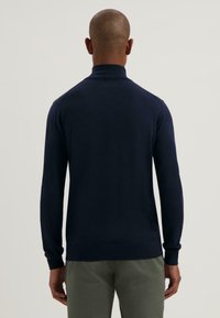 Maglione a collo alto di colore blu navy, con maniche lunghe e orlo aderente. Tessuto lavorato a maglia, con dettagli minimi e senza motivi visibili.