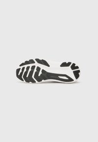 Shoe sole featuring a white base with a black rubber tread pattern; distinct grooves and ridges provide grip and traction.
