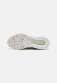 Semelle blanche de basket avec motifs rectangulaires antidérapants, un coussin d’air visible au talon et un petit logo Nike embossé au centre.