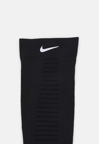 Sorte Nike sokker med et tekstureret design og vandret ribbing, et hvidt Nike-logo øverst og et glat, strækbart stof.