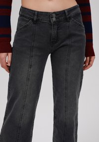 Gray denim wide-leg pants with a high waist, featuring two button closures, front pockets, and contrasting stitching along the seams.