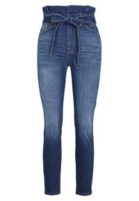 Jeans de mezclilla azul oscuro con cintura alta, que cuentan con un cierre de cinturón atado, ajuste slim y un ligero desgastado en los muslos. Diseño clásico de cinco bolsillos.