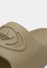 Ταμπά σανδάλι slide κατασκευασμένο από απαλό, υφασμάτινο υλικό, με ανάγλυφο λογότυπο στο πάνω λουράκι. Καμπυλωτό, εργονομικό σχήμα για άνεση.