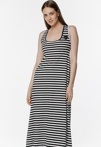 Sukienka maxi w czarno-białe paski, z dekoltem w kształcie łódki i cienkimi ramiączkami, wykonana z miękkiego, stretchowego materiału.