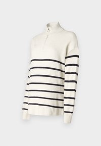Pull crème avec des rayures horizontales noires, col zippé, texture côtelée et coupe décontractée. Manches longues avec un design à épaule tombante.