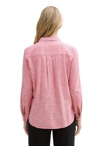 Camicia a quadri rossi con maniche lunghe, yoke posteriore e fessure sui polsini. Realizzata in tessuto leggero con una finitura strutturata.