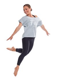 Camiseta de algodón de gran tamaño en azul claro con texto blanco, combinada con leggins negros. Modelo saltando descalzo, mostrando el diseño de ropa deportiva.