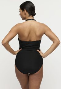 Costume da bagno nero a coste con design a collo all'americana. Presenta una silhouette aderente, schiena scoperta e gambe con taglio medio. Texture liscia in tutta la sua superficie.