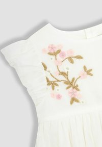 Vestido blanco con bordados florales en rosa y dorado. Mangas acampanadas y detalle de falda fruncida. Tejido suave y texturizado.