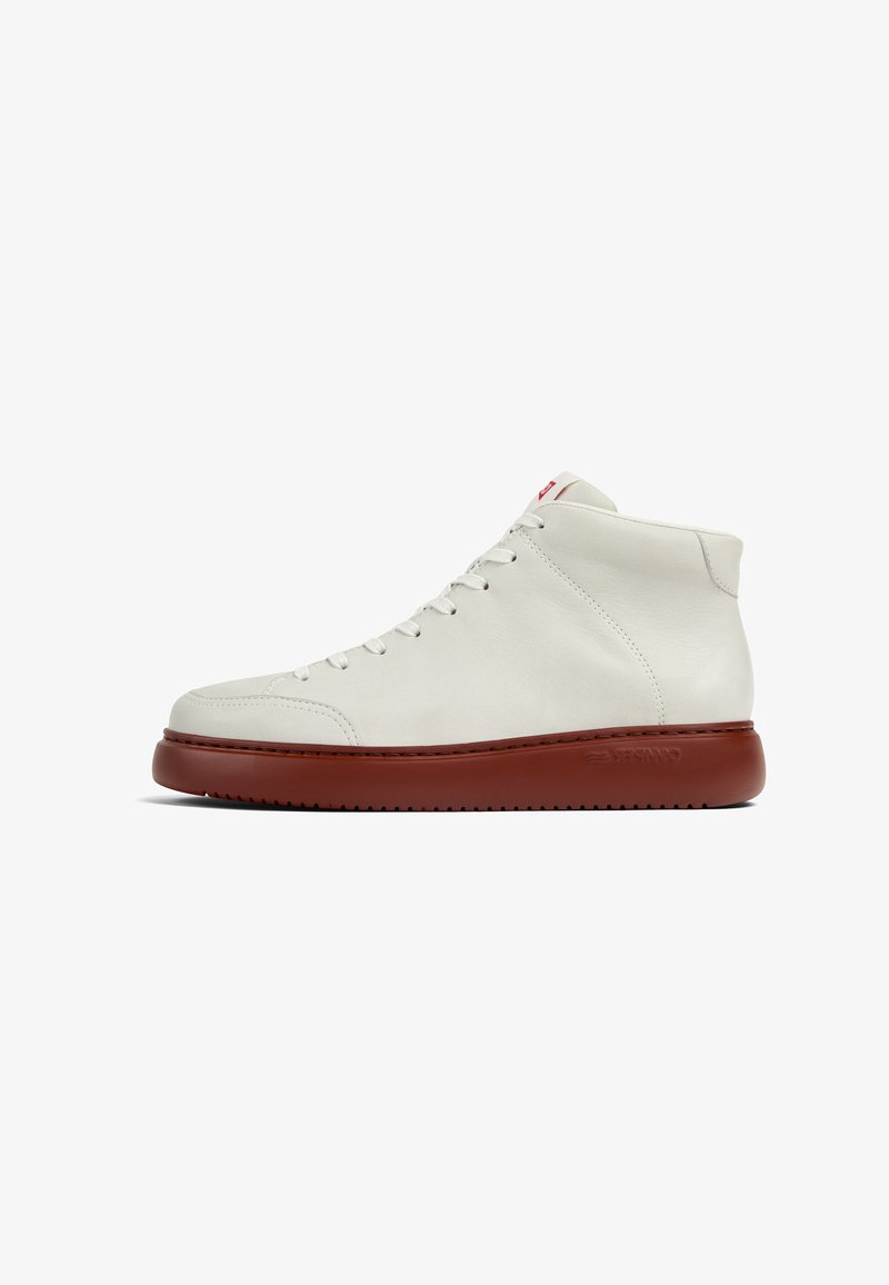 Wysokie trampki wykonane z białej skóry, z zaokrąglonym noskiem, z brązową gumową podeszwą i czerwonym akcentem na języku. Zawiązywana konstrukcja.