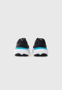 Zapatillas deportivas negras con parte superior de malla, suela blanca y acentos azules en la entresuela. Presentan una textura suave y logotipos en contraste.