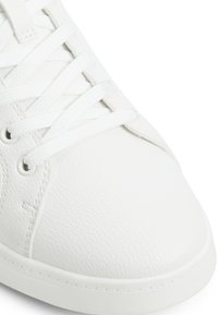 Vita lädersneakers med en slät textur, rund tå och platta vita snörningar. Minimalistisk design med kontrasterande sömmar och öljett detaljer.