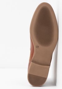 Semelle d'une chaussure en cuir marron indiquant la taille 37 avec une surface antidérapante texturée sur le talon et la partie avant, sur fond blanc.