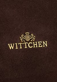 Bruine suède achtergrond met een prominent gouden logo waarop een kroon en twee leeuwen zijn afgebeeld. Het woord "WITTCHEN" is in gouden letters weergegeven.