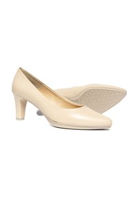 Zapatos de tacón alto de cuero beige con puntera afilada y tacón cuadrado. Textura suave y suela con diseño para mayor adherencia.