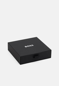 Black box with a smooth texture, featuring a silver "BOSS" logo on the top and a pull tab for opening. Square shape with sharp edges.