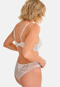 Ensemble de lingerie blanche comprenant un soutien-gorge lisse avec des bretelles réglables et un bas à motif en dentelle. Tissu doux avec un design et une texture délicats.