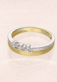 Silber- und Goldring mit drei runden, klaren Edelsteinen; glatte metallische Oberfläche mit einem flachen, gebürsteten Goldband. Innen mit 925 gestempelt.