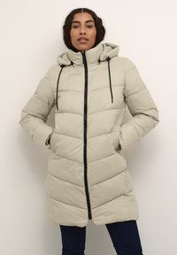 Light beige padded coat with a hood, black zipper, adjustable drawstrings, and chevron quilting design. Front pockets included.