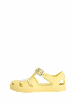Gul plastik sandal med åben tå-design, justerbar spænde rem og udskæringsmønster. Tekstureret sål for godt greb og komfort.